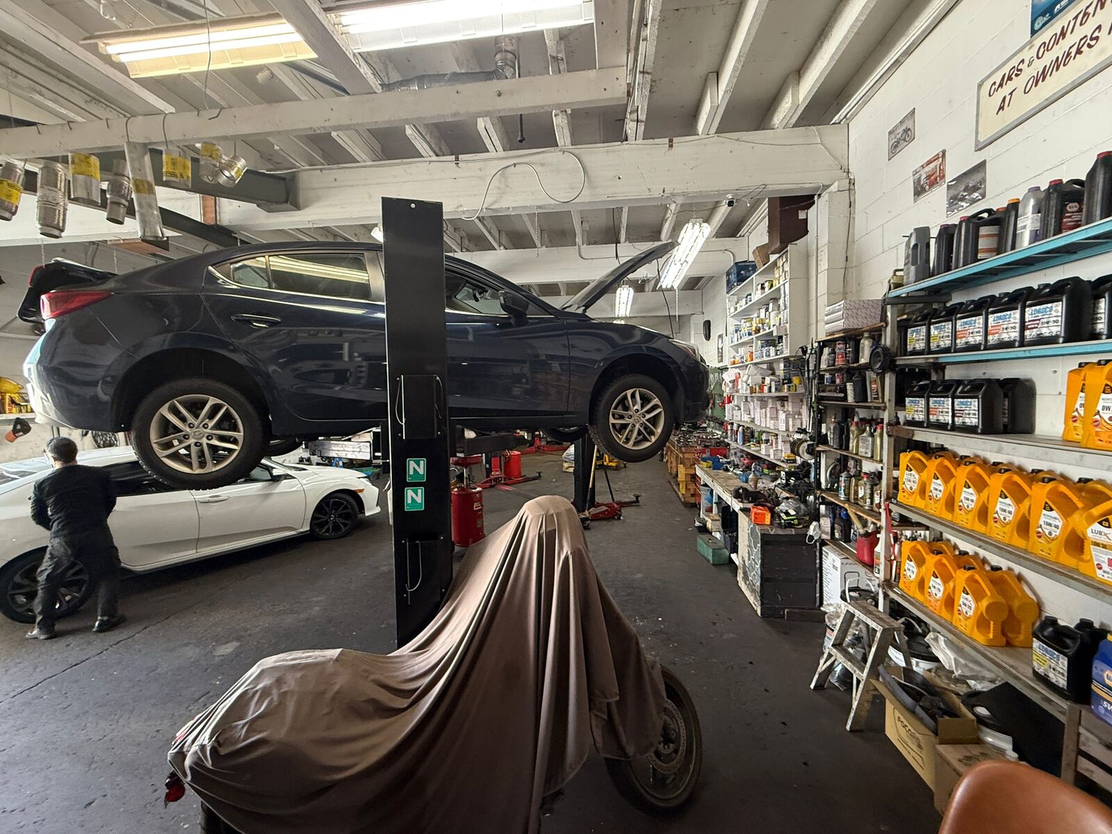 A mechanic and vehicles on hoists in the Hamid Auto bays
